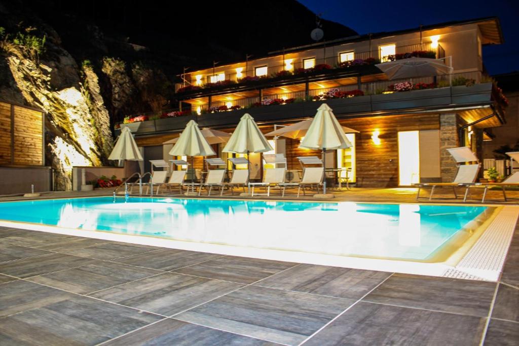 - une piscine avec chaises longues et parasols la nuit dans l'établissement Dascio Salute Ferienwohnung mit Panorama Balkon am See, à Dascio