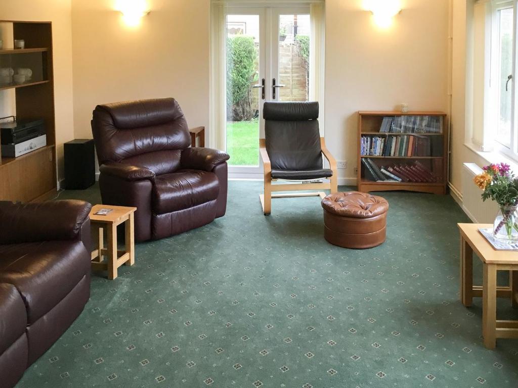 ein Wohnzimmer mit einem Ledersofa und einem Stuhl in der Unterkunft Hedgeways in Fordham