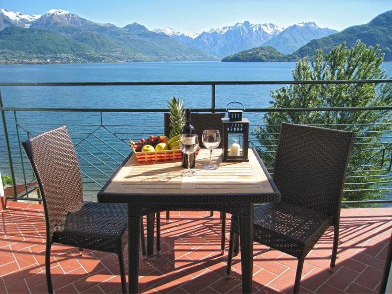 una mesa con un bol de frutas y copas de vino en el balcón en Nido alla Riva - Falco Ferienwohnung en Pianello Del Lario