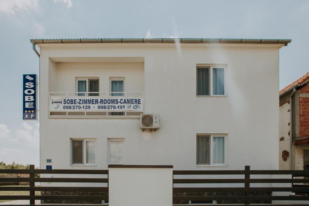 um edifício branco com um sinal na lateral em Sobe Anita-soba s bračnim ležajem em Vukovar