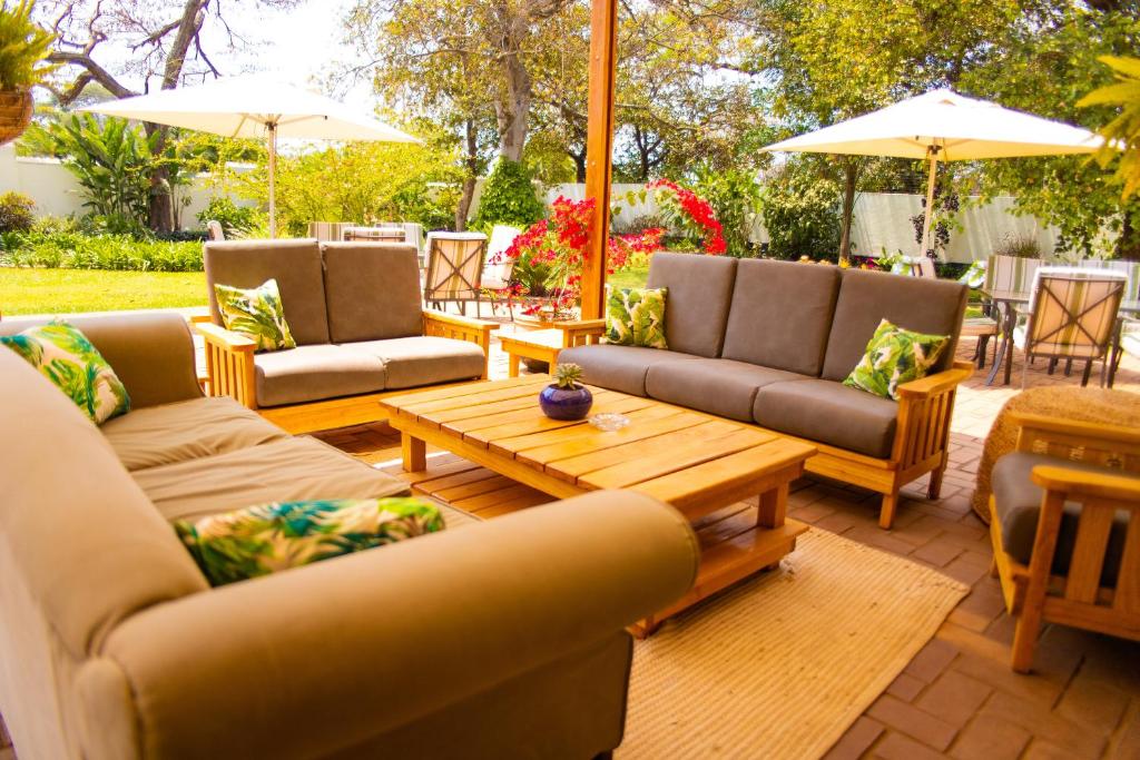 a patio with couches and a coffee table and umbrellas at Burley House by Ulendo in Lilongwe
