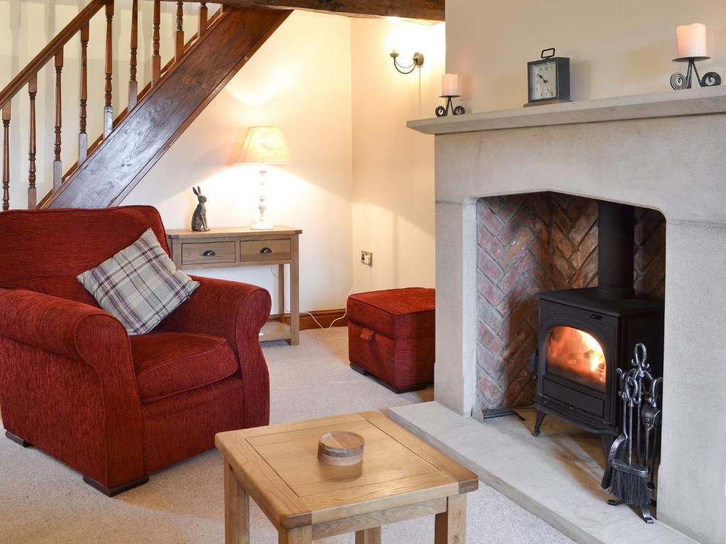 sala de estar con chimenea y silla roja en Far Barsey Cottage, en Sowerby Bridge