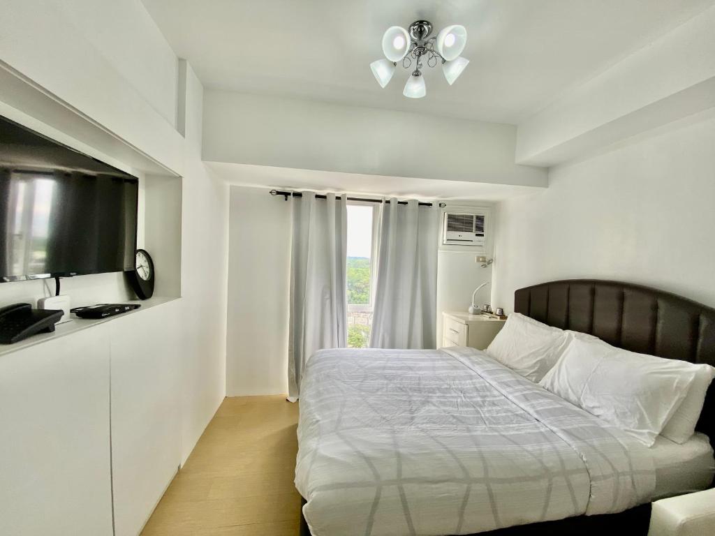 biała sypialnia z łóżkiem i oknem w obiekcie Compact Studio Unit @ Centrio Tower w mieście Cagayan de Oro