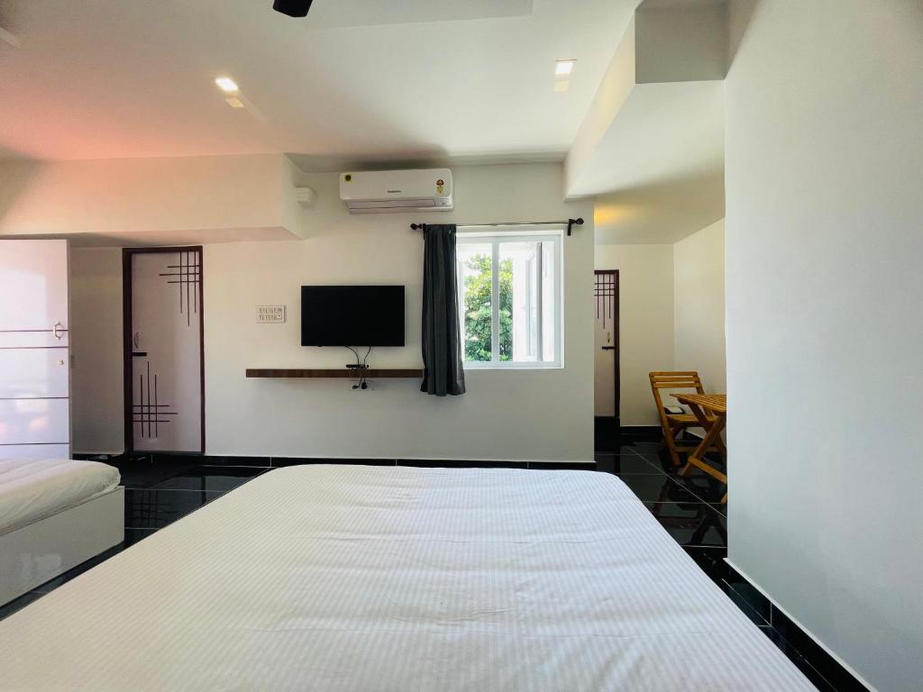 um quarto com uma cama e uma televisão na parede em Villa Bordeaux em Pondicherry
