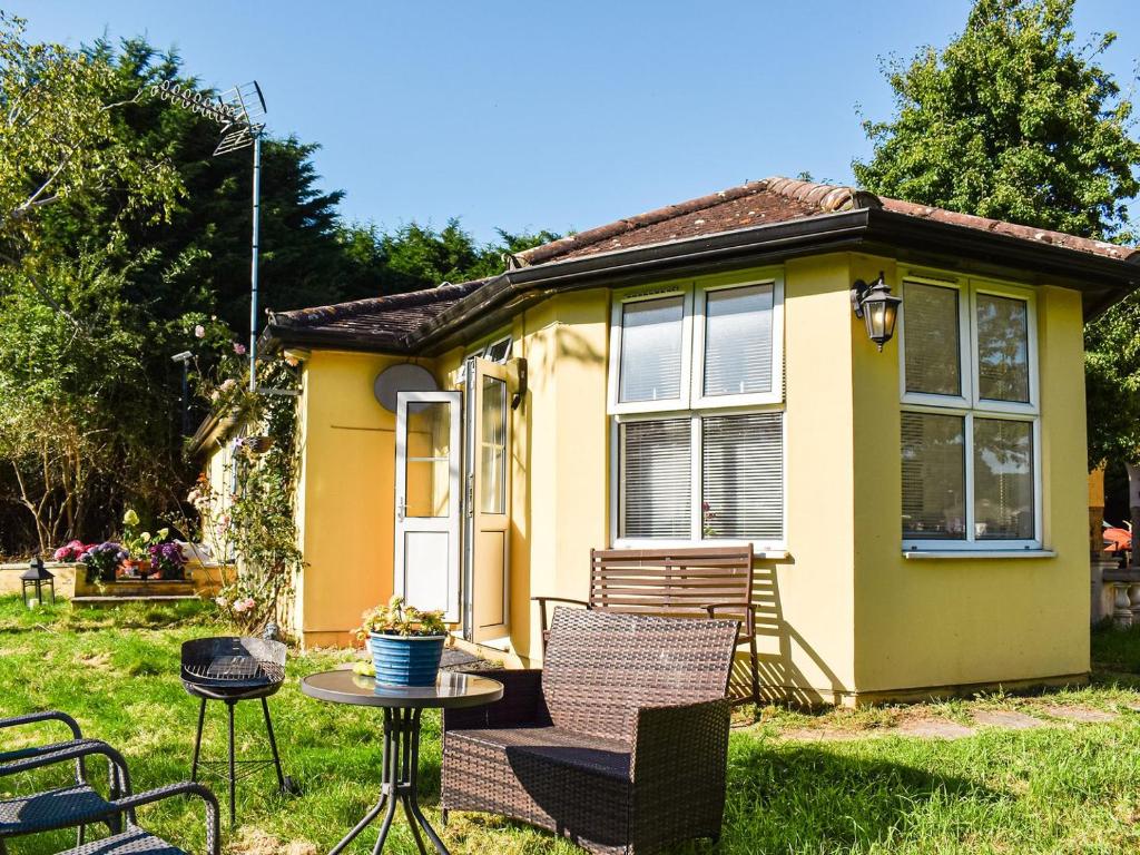 a small yellow house with a table and chairs at Ace Lodge in Hoddesdon