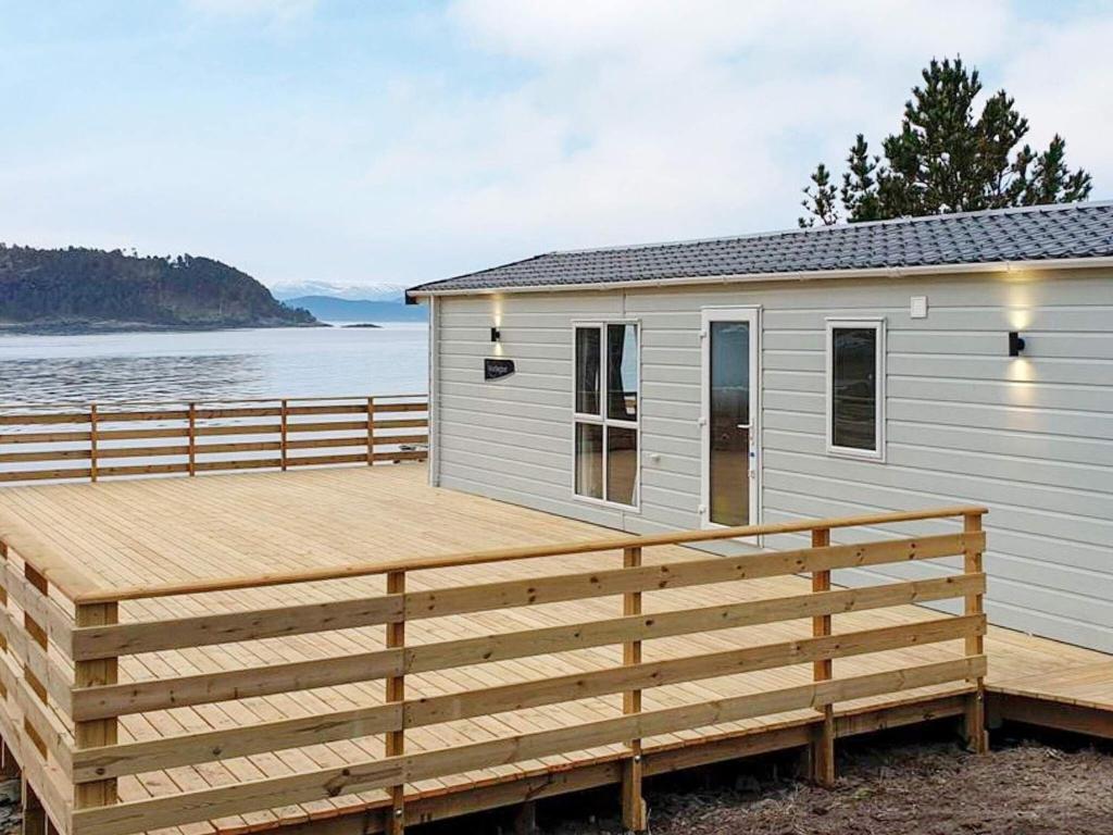 a house with a wooden deck next to the water at Holiday home Tansøy in Tansøy