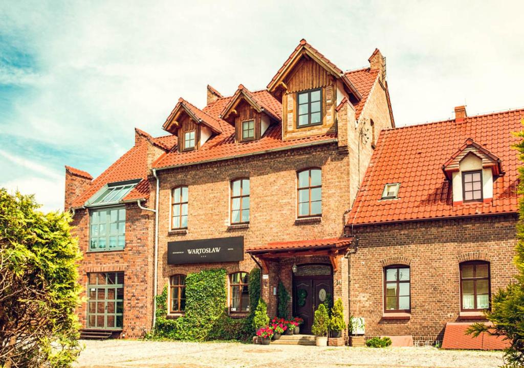 a large brick building with a red roof at Hotel Wartosław in Wronki