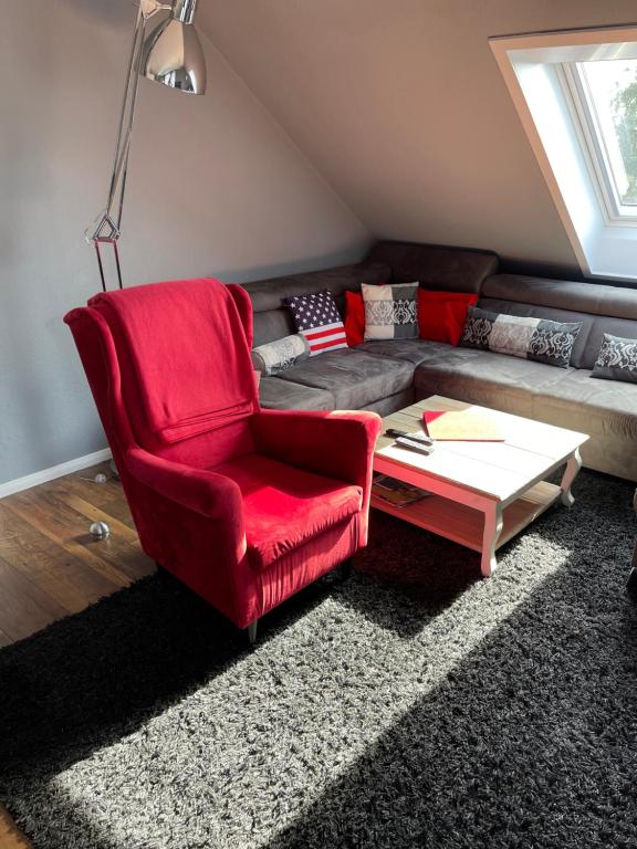 a living room with a red chair and a couch at Ferienwohnung Hampton in Braunlage