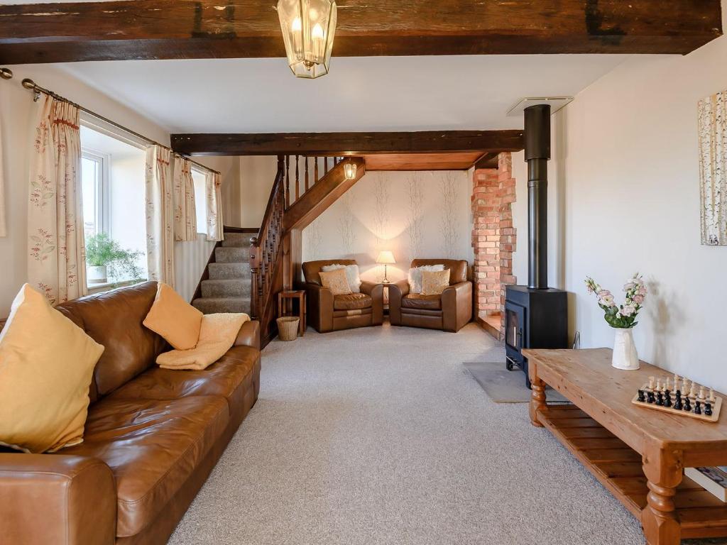 sala de estar con sofá de cuero y TV en Nightingale Lodge, en Ropsley