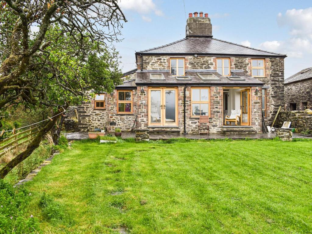 una vista exterior de una casa de piedra con un gran patio en Nant Y Crogwyn, en Penmachno