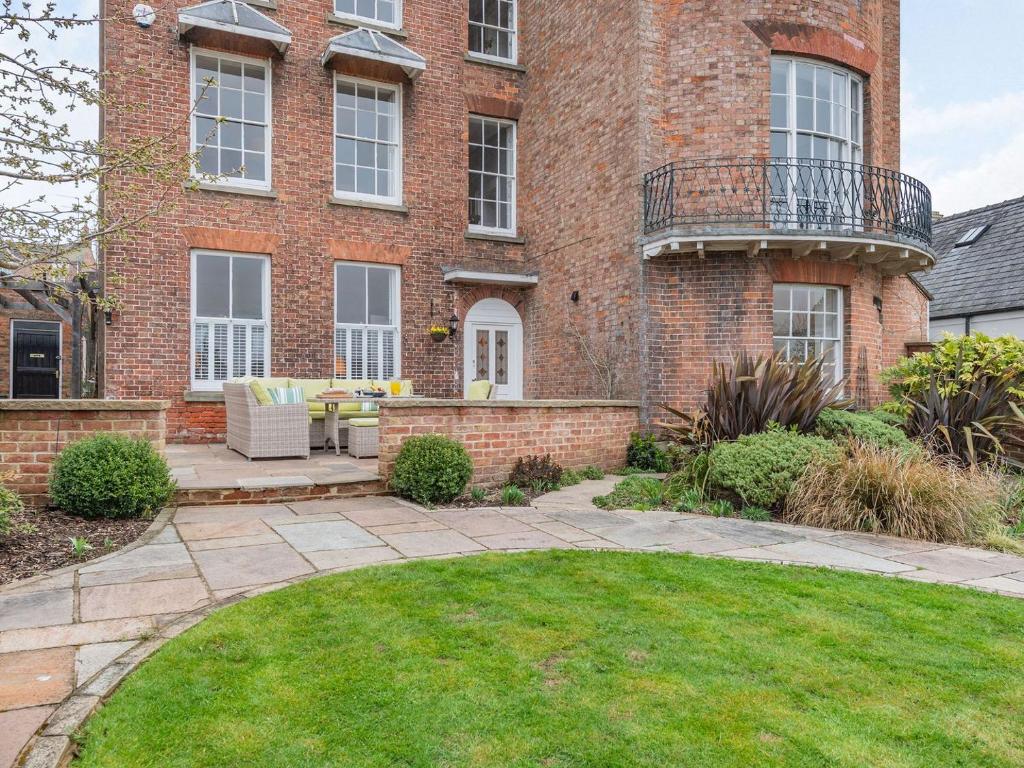 a brick house with a patio and a yard at Bank House Apartment in Newnham