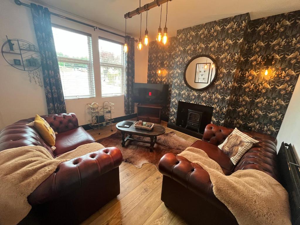 a living room with two leather couches and a fireplace at Modern mid terrace villa, Royston, Barnsley in Royston