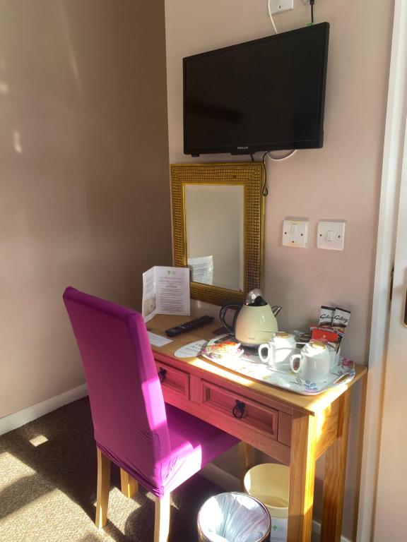 a desk with a mirror and a pink chair at White Heather Guest House in Mablethorpe