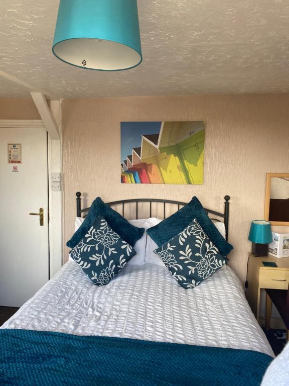 a bedroom with a bed with blue and white pillows at White Heather Guest House in Mablethorpe