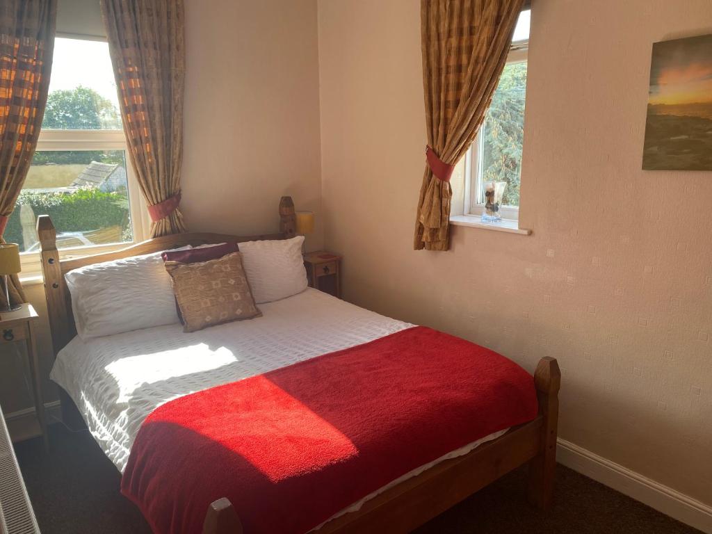 a bedroom with a bed with a red blanket and a window at White Heather Guest House in Mablethorpe