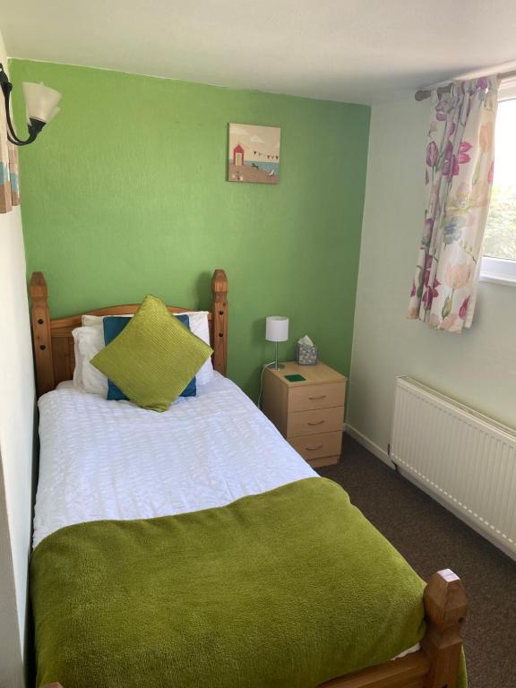 a green bedroom with a bed with a green blanket at White Heather Guest House in Mablethorpe