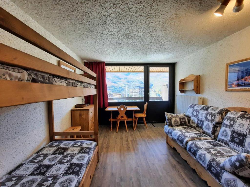 Cette chambre comprend deux lits et une table avec un bureau. dans l'établissement Studio Confort pour 3 avec Balcon Sud, Pied des Pistes, Animaux Acceptés - FR-1-452-289, aux Menuires