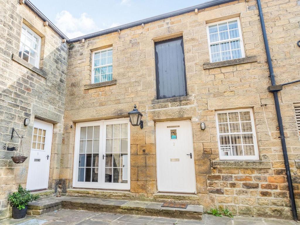 an old brick building with white doors and windows at Claro Cottage - Uk37450 in Pateley Bridge