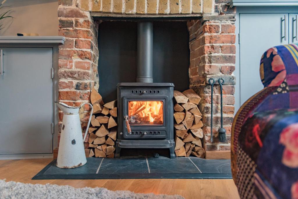 a wood stove in a living room with a fireplace at Cow and Cockle - quirky cottage in the centre of Deal in Deal