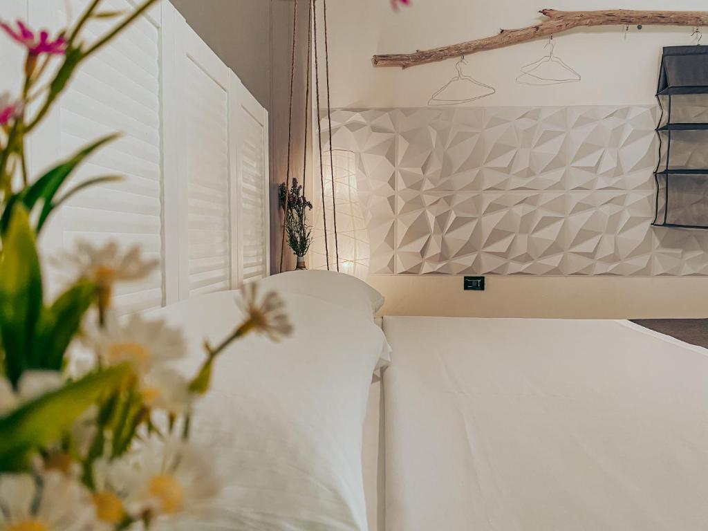 1 dormitorio con 1 cama con sábanas blancas y flores en Il Ritrovo di Ulisse, en Villa San Giovanni