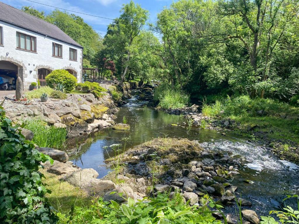 a stream in front of a house and a house at Forge Mill Cottage in Dalbeattie