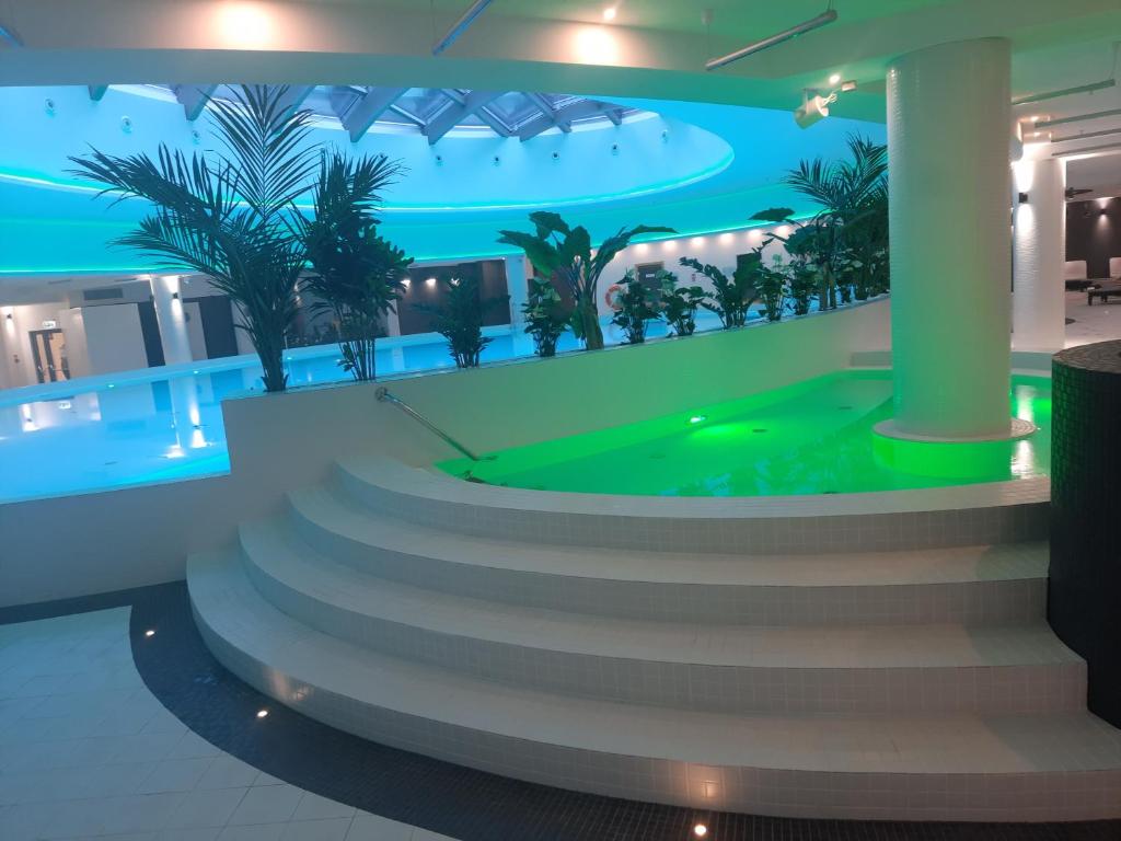 a lobby with a pool with palm trees on the wall at Hanza Tower Sunny Apartment in Szczecin