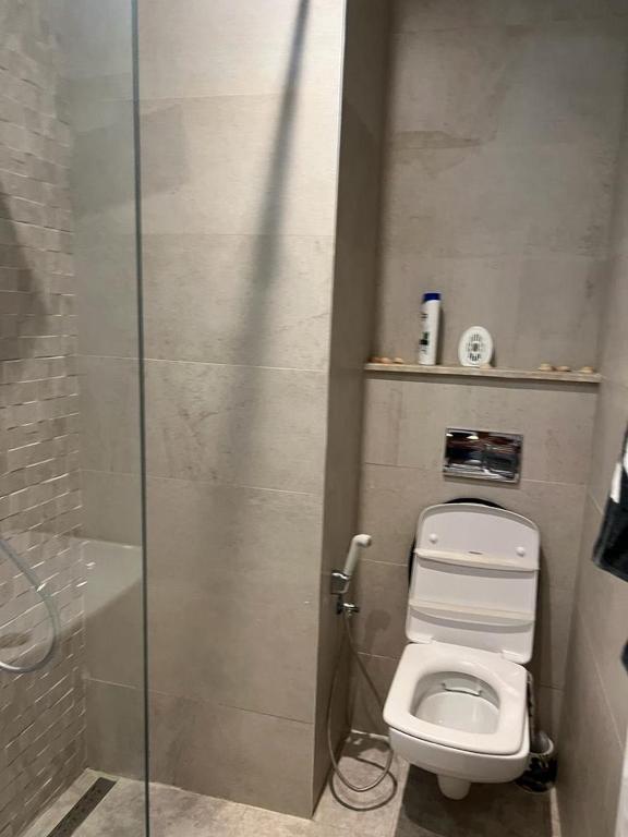 a bathroom with a toilet and a glass shower stall at Superbe Appartement kantaoui sousse in Sousse