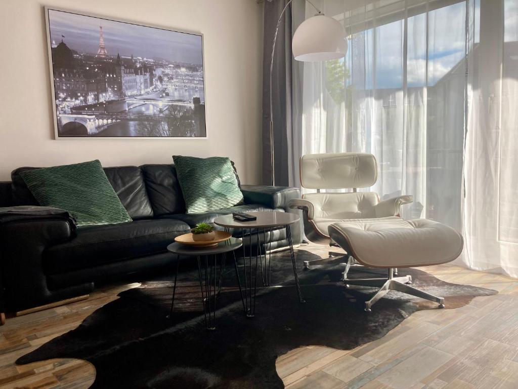 ein Wohnzimmer mit einem schwarzen Sofa und einem Stuhl in der Unterkunft Living at Saarpartments -Adults Only- 2 Bedrooms, Netflix - Business & Holiday Apartments for Long- and Short term Stay, 3 min to Train Station and Europa Galerie in Saarbrücken