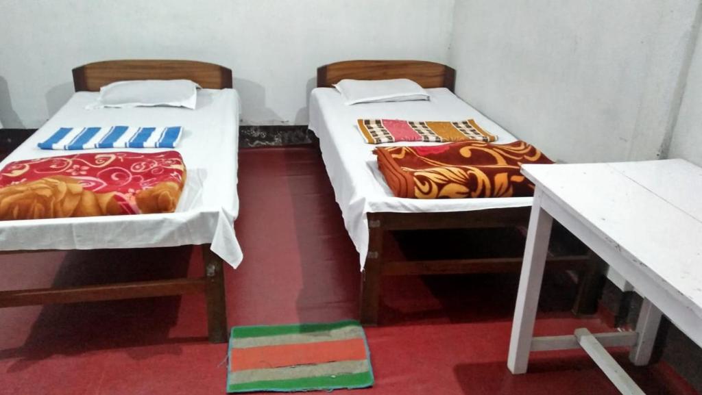 two beds in a room with a desk and a table at Subansiri lodge in Majuli