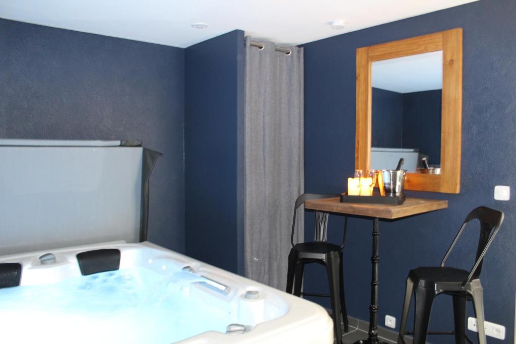 uma banheira num quarto com um espelho e bancos em Althéa, gîte de charme et bien être em Fontenay-le-Comte