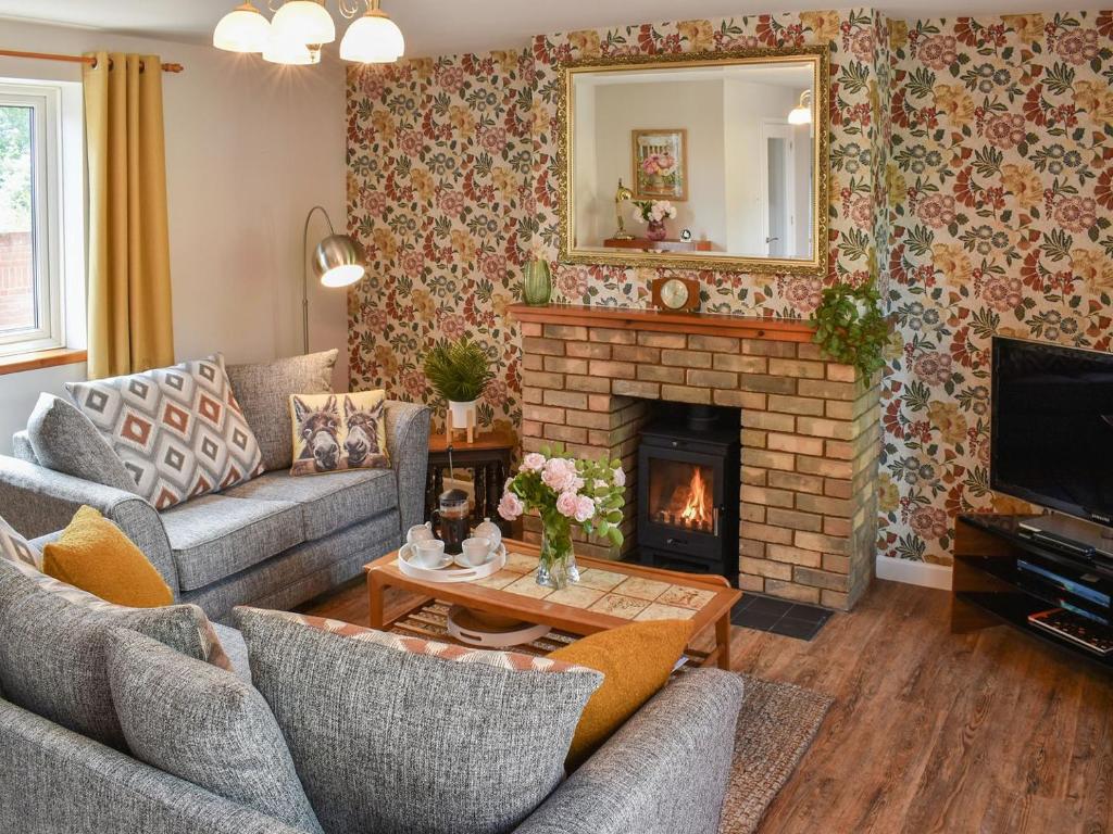 a living room with two couches and a fireplace at Hawks Mill Cottage in Needham Market