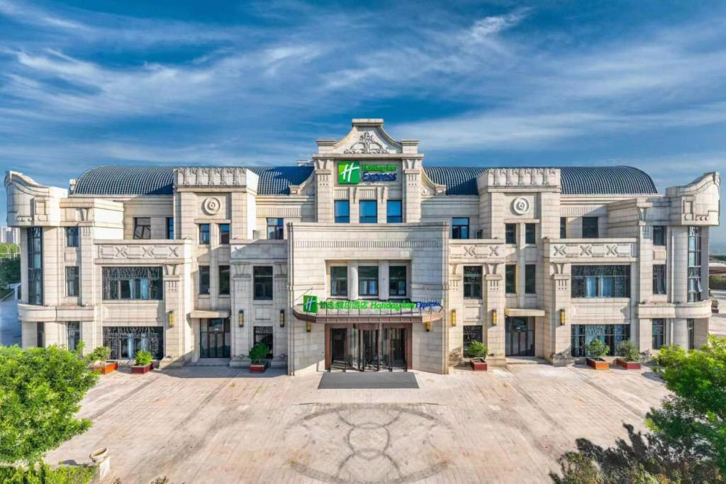 a large white building with a green sign on it at Holiday Inn Express Tianjin Binhai, an IHG Hotel in Binhai