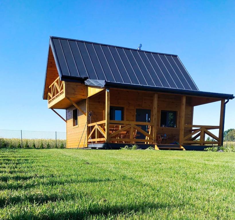 a log cabin with a solar roof on a grass field at Domek nad Nieliszem in Nielisz