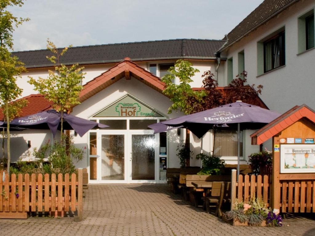 ein Hotel mit Tischen und Sonnenschirmen davor in der Unterkunft Gasthaus Bonneberger Hof in Vlotho