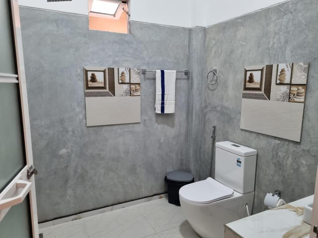 a bathroom with a white toilet and a sink at Thara Cabana in Bentota