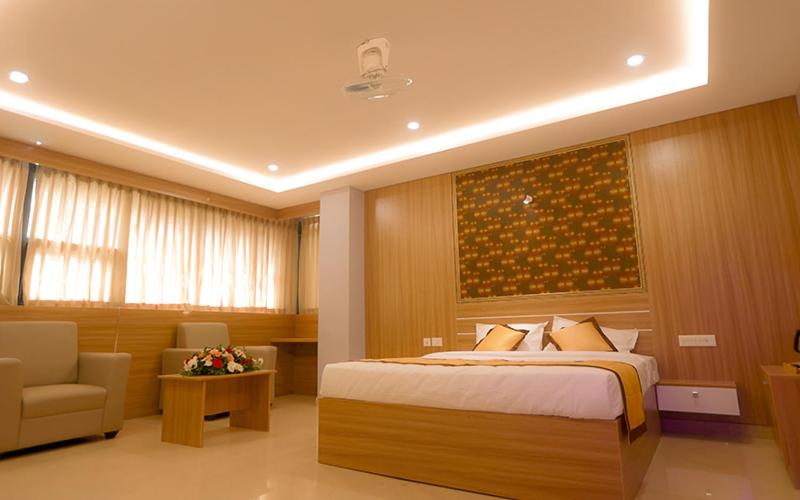 a bedroom with a bed and a couch and a chair at Hotel Emirates in Kānnangād