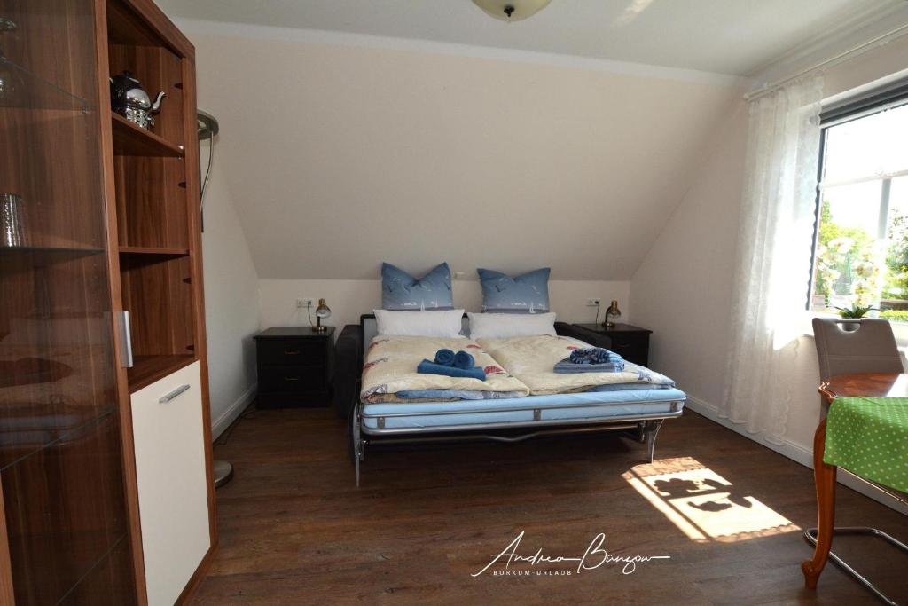 ein Schlafzimmer mit einem Bett mit blauen Kissen und einem Fenster in der Unterkunft Pension Lütje Huske Zimmer4 in Südbrookmerland