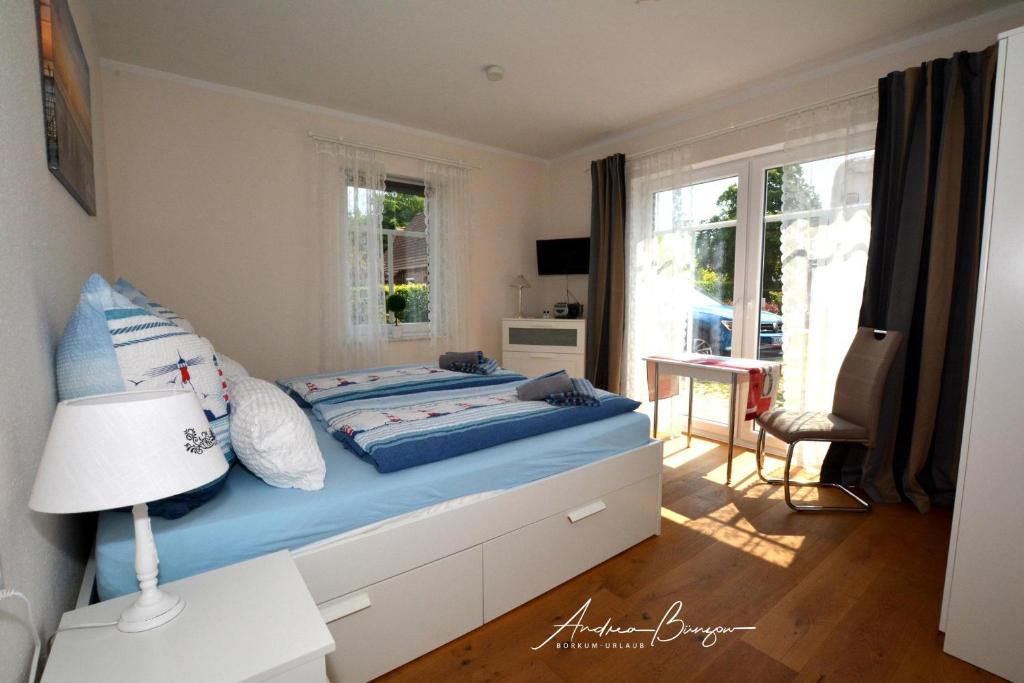 a bedroom with a bed with blue sheets and a window at Pension Lütje Huske Zimmer 2 in Südbrookmerland