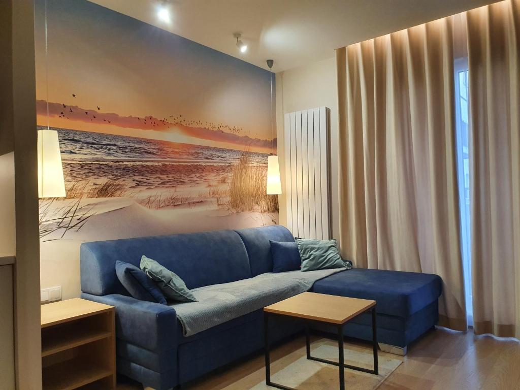 una sala de estar con un sofá azul y una pintura en Apartament Gliwice centrum, z garażem, en Gliwice