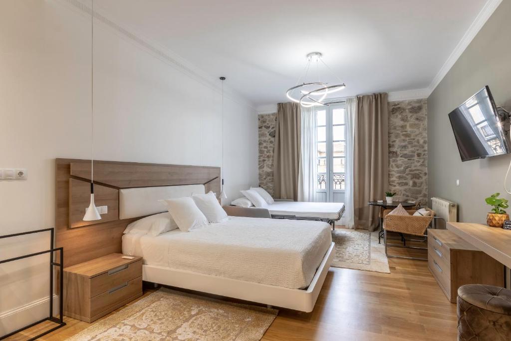 a bedroom with a bed and a living room at Habitaciones Apartamento B&B Plaza Nueva 8 in Bilbao