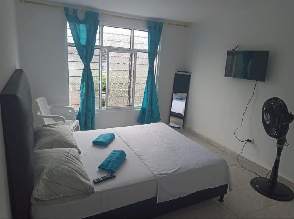 een slaapkamer met een bed, een ventilator en een raam bij Casa Olimpico Hostal in Cali