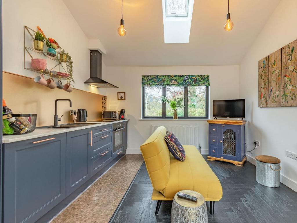 a kitchen with blue cabinets and a yellow chair at Stars Special Sanctuary - Uk36785 in Sutton Valence