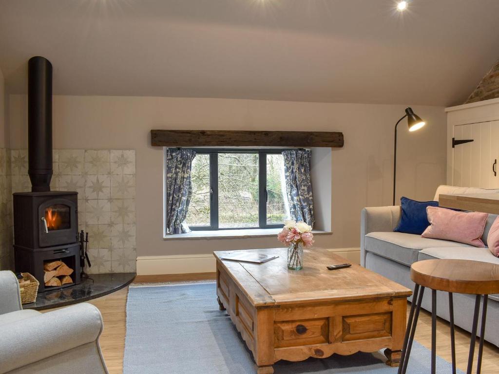 a living room with a couch and a wood stove at The Old Shippon At New Ringstones Farm in Mellor