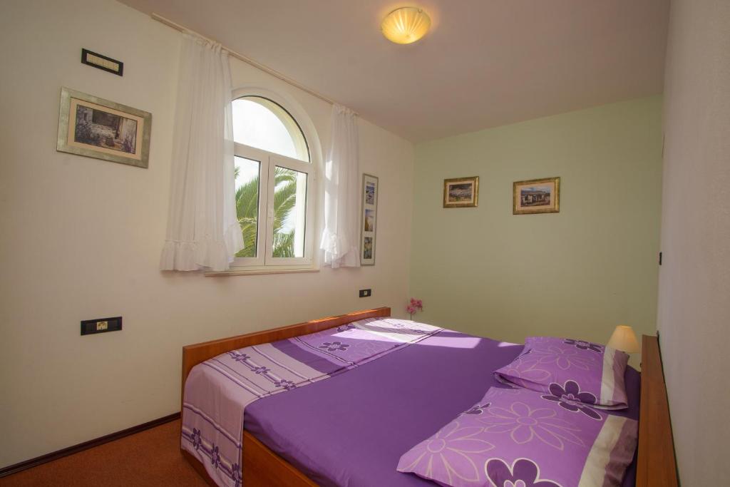 1 dormitorio con cama morada y ventana en Apartments Jerkunica, en Rogoznica