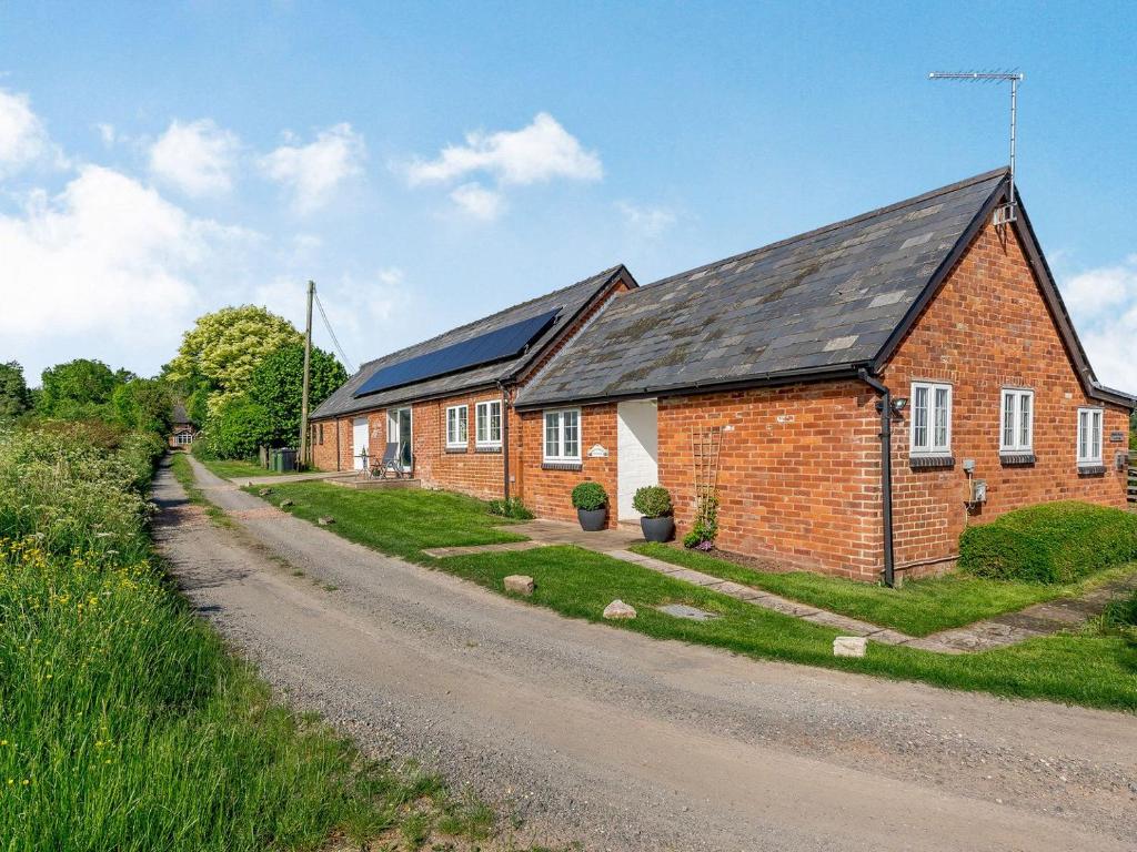 a brick house with solar panels on a road at Wheelhouse Cottage in Ullingswick