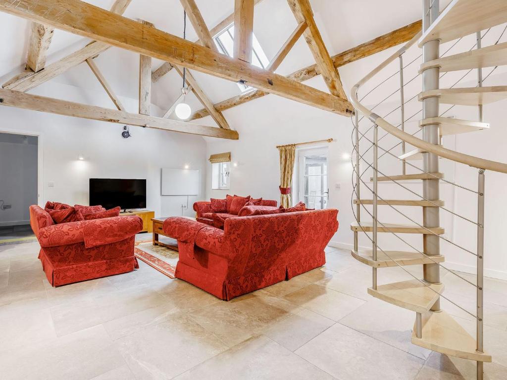 a living room with two red couches and a television at Kings Barn in Weston under Lizard