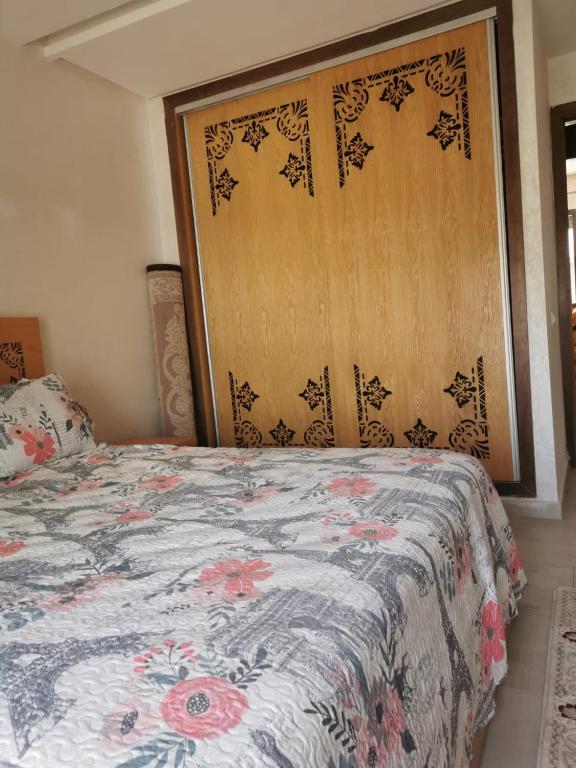 a bedroom with a bed with a floral bedspread at mehdiya plage in Kenitra