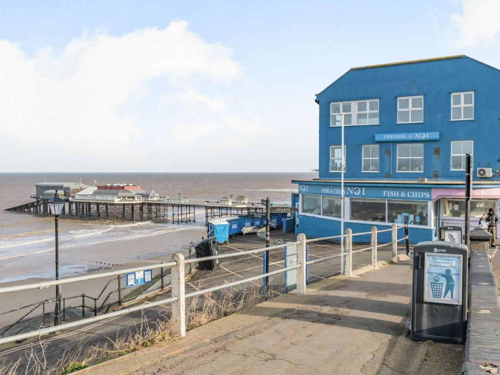 a blue building on the beach with a pier at The Perch-uk37325 in Cromer