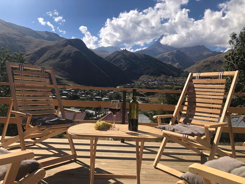two chairs and a table on a deck with mountains at Hotel Nestt in Stepantsminda