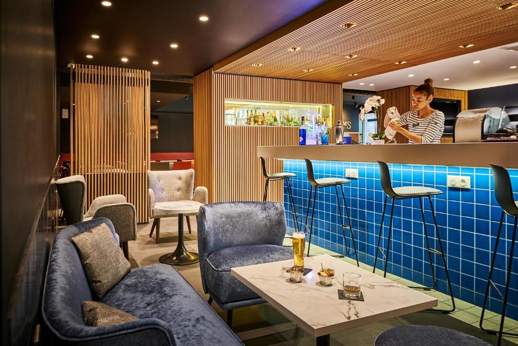 a restaurant with a table and chairs and a woman at Hotel Campanile Paris-Bercy Village in Paris